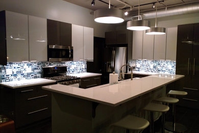 Large minimalist u-shaped eat-in kitchen photo in Other with flat-panel cabinets, gray cabinets, blue backsplash, stainless steel appliances and an island
