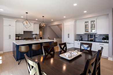 Example of a large transitional l-shaped light wood floor and brown floor eat-in kitchen design in Other with an undermount sink, recessed-panel cabinets, white cabinets, quartz countertops, gray backsplash, ceramic backsplash, paneled appliances, an island and white countertops