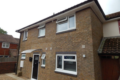 This is an example of a large and yellow modern two floor brick semi-detached house in Sussex with a hip roof and a tiled roof.