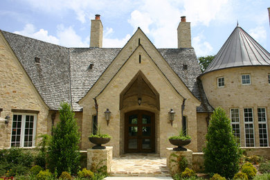 Inspiration for a traditional two-storey beige exterior in Other with stone veneer and a hip roof.