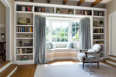 Inspiration for a large enclosed medium tone wood floor and brown floor living room remodel in Santa Barbara with beige walls, a standard fireplace and a plaster fireplace
