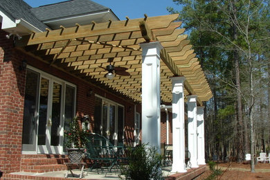 Example of a mid-sized classic backyard concrete paver patio design in Other with a pergola