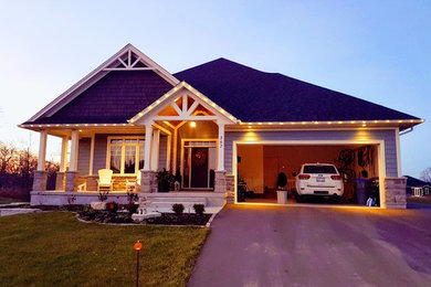 Example of a mid-sized arts and crafts blue one-story concrete fiberboard house exterior design in Toronto with a hip roof and a shingle roof