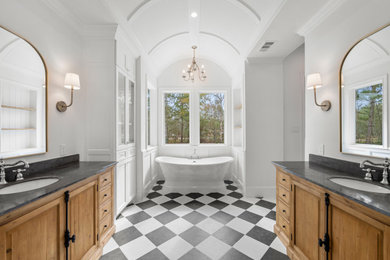 Inspiration for a large timeless master porcelain tile, black floor, double-sink, vaulted ceiling and wall paneling freestanding bathtub remodel in Houston with shaker cabinets, light wood cabinets, white walls, marble countertops, gray countertops and a freestanding vanity