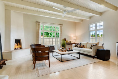 Example of a large trendy formal and open concept light wood floor and beige floor living room design in Other with white walls, a corner fireplace, a plaster fireplace and no tv