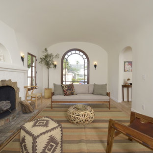 Diseño de salón para visitas abierto, mediterráneo, de tamaño medio, con paredes blancas, suelo de madera clara, chimenea tradicional y marco de chimenea de baldosas y/o azulejos