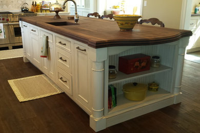 Example of a country kitchen design in Boston with dark wood cabinets and wood countertops