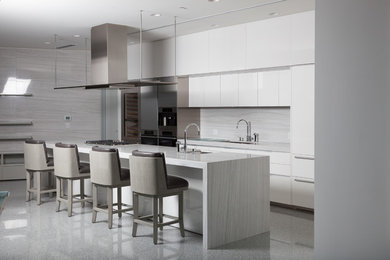 Mid-sized trendy galley eat-in kitchen photo in Vancouver with white cabinets, white backsplash, stainless steel appliances, an island, an undermount sink, flat-panel cabinets, quartz countertops and stone slab backsplash