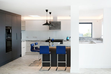 This is an example of a medium sized contemporary grey and white u-shaped open plan kitchen in Cambridgeshire with flat-panel cabinets, grey cabinets, quartz worktops and feature lighting.