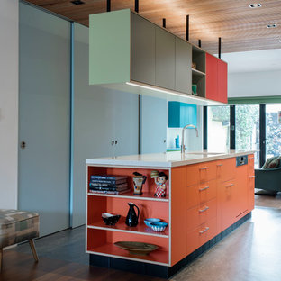 Exemple d'une arrière-cuisine parallèle tendance de taille moyenne avec un évier 1 bac, un placard à porte plane, des portes de placard oranges, un plan de travail en terrazzo, un électroménager en acier inoxydable, un sol en linoléum et un îlot central.