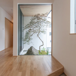 他の地域の片開きドアモダンスタイルのおしゃれな玄関 (白い壁、木目調のドア、グレーの床) の写真