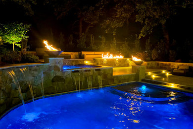 Exempel på en mellanstor klassisk anpassad pool på baksidan av huset, med en fontän och naturstensplattor
