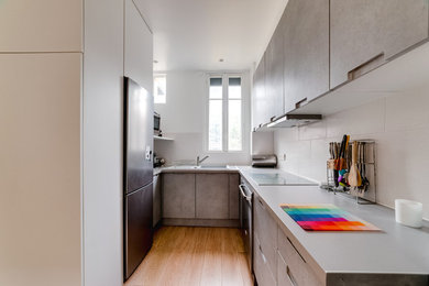 Exemple d'une grande cuisine ouverte tendance en U avec un évier encastré, un placard à porte plane, des portes de placard grises, un plan de travail en stratifié, une crédence blanche, une crédence en carreau de porcelaine, un électroménager en acier inoxydable, sol en stratifié, aucun îlot, un sol beige et un plan de travail gris.