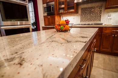 Eat-in kitchen - mid-sized transitional u-shaped porcelain tile eat-in kitchen idea in San Francisco with a farmhouse sink, flat-panel cabinets, dark wood cabinets, granite countertops, white backsplash, glass tile backsplash, stainless steel appliances and an island