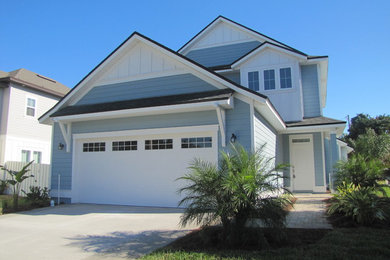 This is an example of a large beach style two-storey blue house exterior in Jacksonville with wood siding, a gable roof and a shingle roof.
