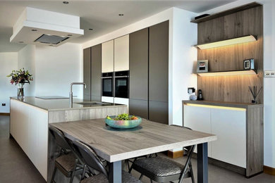 Medium sized modern l-shaped open plan kitchen in Other with a submerged sink, flat-panel cabinets, white cabinets, quartz worktops, black appliances, an island, grey floors and brown worktops.
