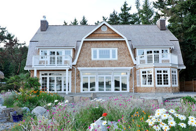 This is an example of a beach style two-storey exterior in Vancouver with wood siding and a gambrel roof.
