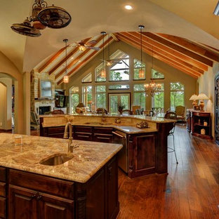 Large traditional kitchen pantry remodeling - Kitchen pantry - large traditional u-shaped medium tone wood floor and brown floor kitchen pantry idea in Dallas with an undermount sink, raised-panel cabinets, dark wood cabinets, granite countertops, beige backsplash, stone tile backsplash, stainless steel appliances and two islands