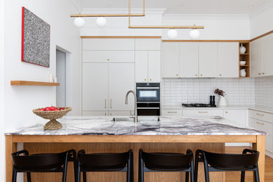 Mid-sized contemporary l-shaped kitchen in Brisbane with an undermount sink, white cabinets, marble benchtops, white splashback, ceramic splashback, panelled appliances, medium hardwood floors, a peninsula, brown floor, flat-panel cabinets and white benchtop.