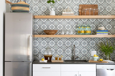 Mid-sized trendy concrete floor and gray floor kitchen photo in Austin with an undermount sink, flat-panel cabinets, white cabinets, multicolored backsplash, cement tile backsplash and stainless steel appliances