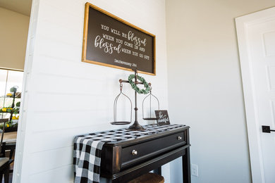 Example of a mid-sized farmhouse medium tone wood floor and brown floor entryway design in Austin with gray walls and a dark wood front door