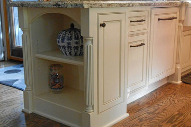 Mid-sized elegant u-shaped medium tone wood floor enclosed kitchen photo in Los Angeles with a farmhouse sink, beaded inset cabinets, white cabinets, granite countertops, brown backsplash, stainless steel appliances and an island