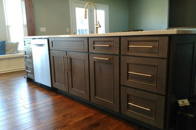 Inspiration for a mid-sized transitional l-shaped dark wood floor and brown floor eat-in kitchen remodel in Other with a single-bowl sink, shaker cabinets, white cabinets, quartzite countertops, gray backsplash, ceramic backsplash, stainless steel appliances and an island
