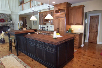 Kitchen pantry - single-wall medium tone wood floor kitchen pantry idea in Other with an undermount sink, raised-panel cabinets, medium tone wood cabinets, granite countertops, beige backsplash, ceramic backsplash, stainless steel appliances and an island