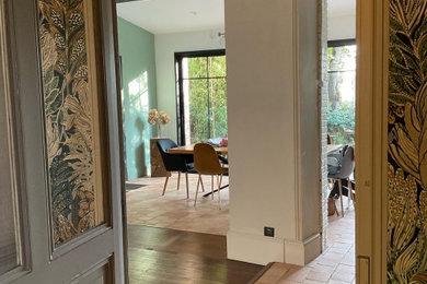 Aménagement d'une salle à manger ouverte sur le salon moderne avec un mur vert, un sol en carrelage de céramique et un sol rouge.