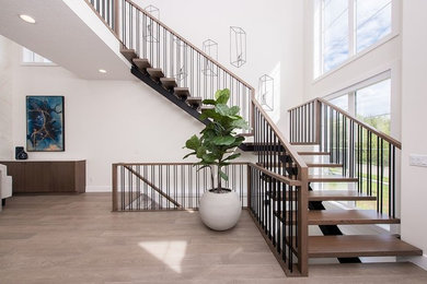 Photo of a contemporary wood staircase in Edmonton with open risers and metal railing.