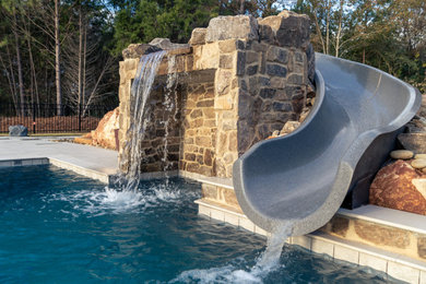 Imagen de piscina con tobogán grande rectangular en patio trasero con entablado