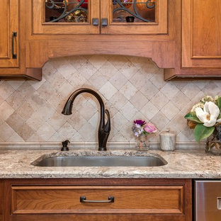 Выдающиеся фото от архитекторов и дизайнеров интерьера: маленькая угловая кухня-гостиная в средиземноморском стиле с врезной раковиной, фасадами с декоративным кантом, коричневыми фасадами, столешницей из кварцевого композита, бежевым фартуком, фартуком из травертина, техникой из нержавеющей стали, светлым паркетным полом, островом и желтым полом