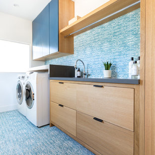 ロサンゼルスの大きいコンテンポラリースタイルのおしゃれな洗濯室 (アンダーカウンターシンク、フラットパネル扉のキャビネット、クオーツストーンカウンター、青い壁、左右配置の洗濯機・乾燥機、グレーのキッチンカウンター、中間色木目調キャビネット、青い床) の写真