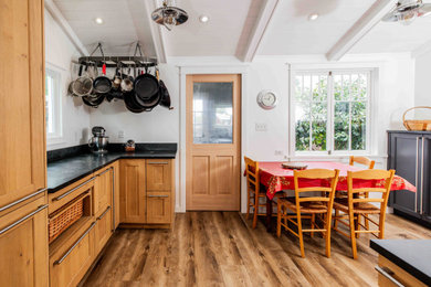 Mid-sized cottage galley medium tone wood floor and brown floor enclosed kitchen photo in San Francisco with an undermount sink, shaker cabinets, medium tone wood cabinets, solid surface countertops, white backsplash, subway tile backsplash, stainless steel appliances, no island and black countertops