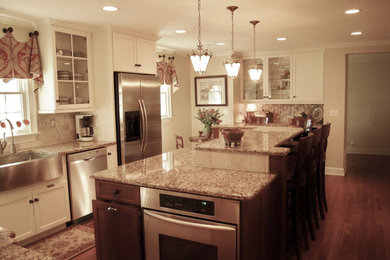 Kitchen - traditional medium tone wood floor and brown floor kitchen idea in Charlotte with a farmhouse sink, granite countertops, travertine backsplash, stainless steel appliances and an island