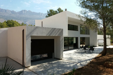 Imagen de fachada de casa blanca de tamaño medio de dos plantas con revestimiento de estuco y tejado de teja de barro