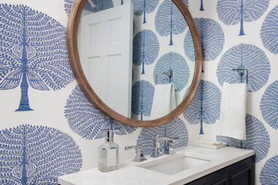 Transitional wallpaper powder room photo in Other with blue cabinets