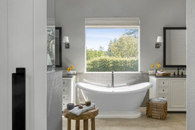 This is an example of a large country master bathroom in San Francisco with furniture-like cabinets, a freestanding tub, a corner shower, a one-piece toilet, gray tile and an open shower.