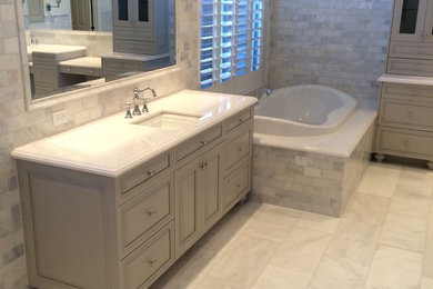 Example of a classic master marble floor corner bathtub design in Phoenix with raised-panel cabinets, gray cabinets, an undermount sink and marble countertops