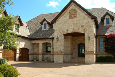 Example of an ornate beige one-story mixed siding exterior home design in Dallas with a gambrel roof