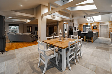 Large classic galley open plan kitchen in Other with an integrated sink, raised-panel cabinets, grey cabinets, composite countertops, white splashback, black appliances, ceramic flooring, an island, grey floors, white worktops and a vaulted ceiling.