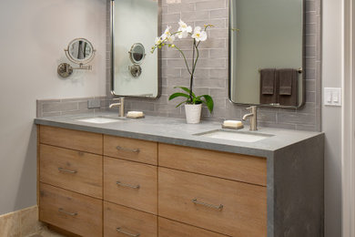 Inspiration for a mid-sized transitional kids' gray tile travertine floor, beige floor and double-sink bathroom remodel in San Diego with flat-panel cabinets, medium tone wood cabinets, a one-piece toilet, gray walls, an undermount sink, solid surface countertops, gray countertops and a built-in vanity