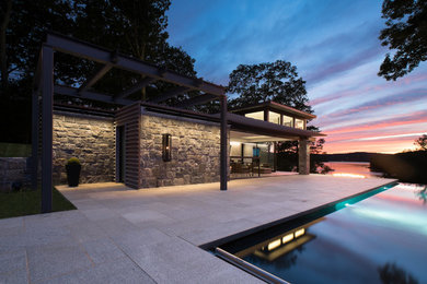 Inspiration for a large contemporary beige house exterior in New York with stone veneer and a flat roof.