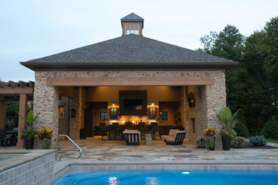 This is an example of a mid-sized country backyard rectangular lap pool in Indianapolis with a pool house and natural stone pavers.