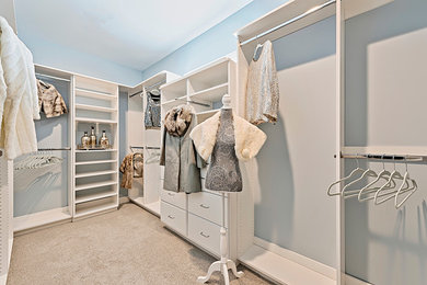 Example of a large gender-neutral carpeted and beige floor walk-in closet design in Other with flat-panel cabinets and white cabinets