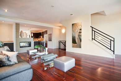 Example of a mid-sized trendy open concept dark wood floor family room design in Denver with a two-sided fireplace, beige walls, a tile fireplace and no tv