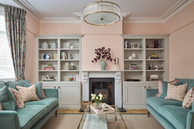 This is an example of a medium sized classic living room in Kent with pink walls, medium hardwood flooring, a wood burning stove, a stone fireplace surround, no tv and a dado rail.