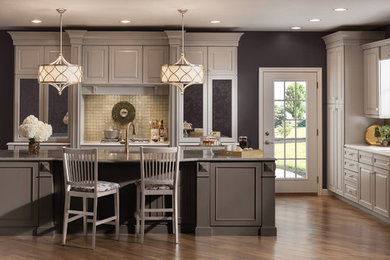 Inspiration for a large transitional l-shaped medium tone wood floor enclosed kitchen remodel in Chicago with an undermount sink, raised-panel cabinets, beige cabinets, granite countertops, beige backsplash, mosaic tile backsplash, paneled appliances and an island