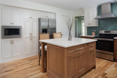 Inspiration for a mid-sized contemporary galley medium tone wood floor and brown floor enclosed kitchen remodel in Philadelphia with shaker cabinets, medium tone wood cabinets, quartz countertops, blue backsplash, subway tile backsplash, stainless steel appliances, an island and white countertops