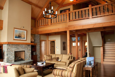 Cette photo montre un grand salon craftsman ouvert avec un sol en bois brun, un manteau de cheminée en pierre, un mur beige et une cheminée standard.